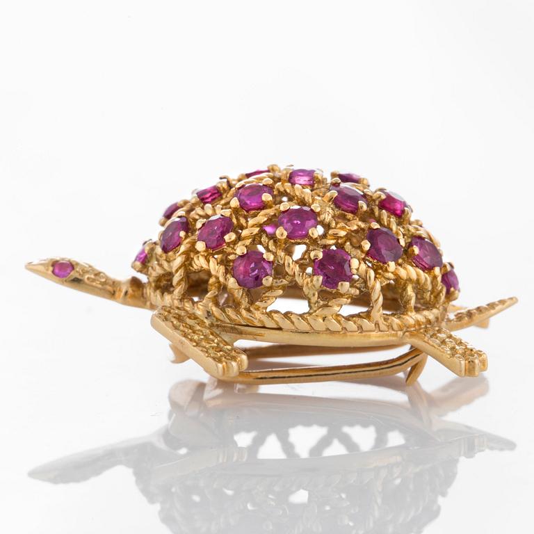 A Cartier turtle brooch in 18K gold set with rubies.