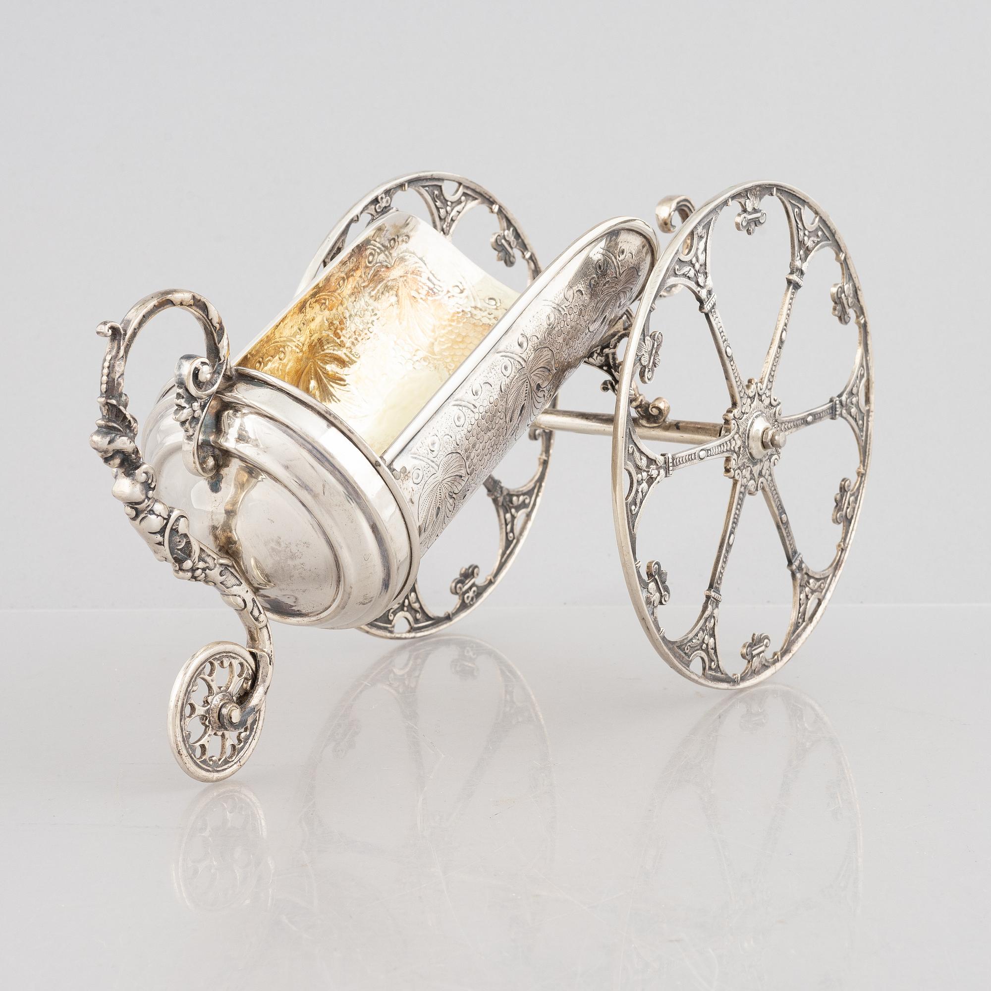 A silver bottle holder with wheels, 20th Century.