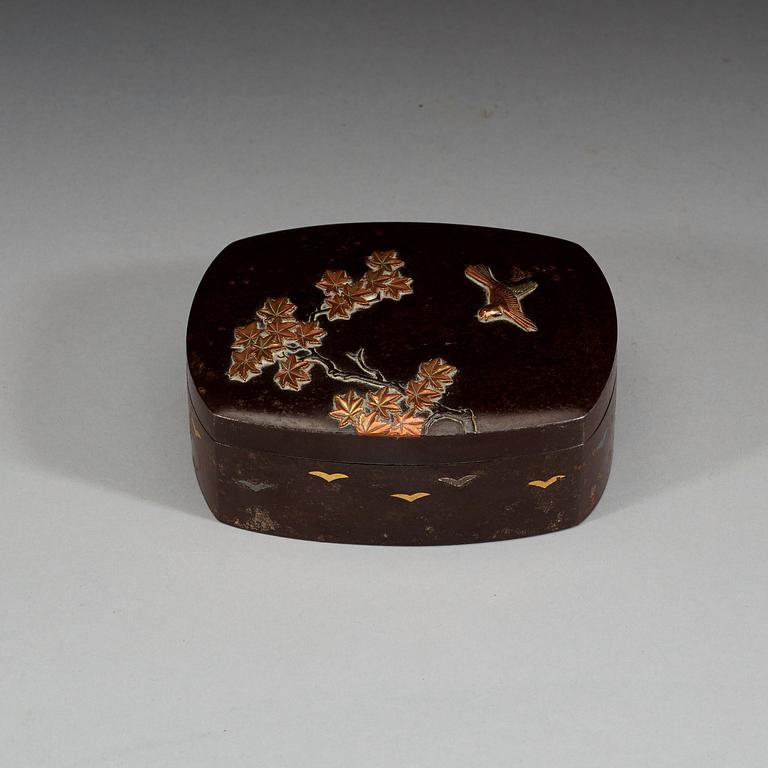 An iron and silvered box decorated with tree branches and a bird in copper and gold, Japan, 19th century.