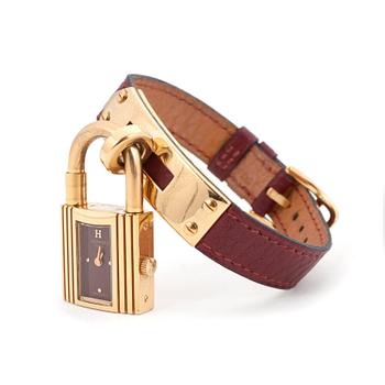 715. HERMÈS, a burgundy red leather braclet with 14k gold plated watch, "Kelly Lock".
