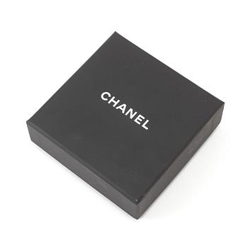 A white metal brooch by Chanel.