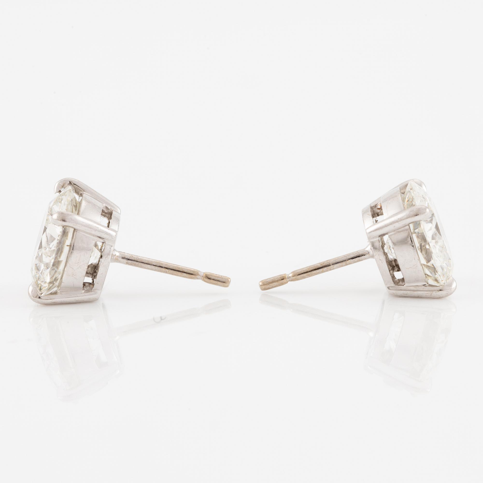 A pair of earrings in 18K white gold set with two round brilliant-cut diamonds.