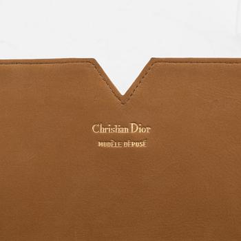 Christian Dior, a tan leather clutch.