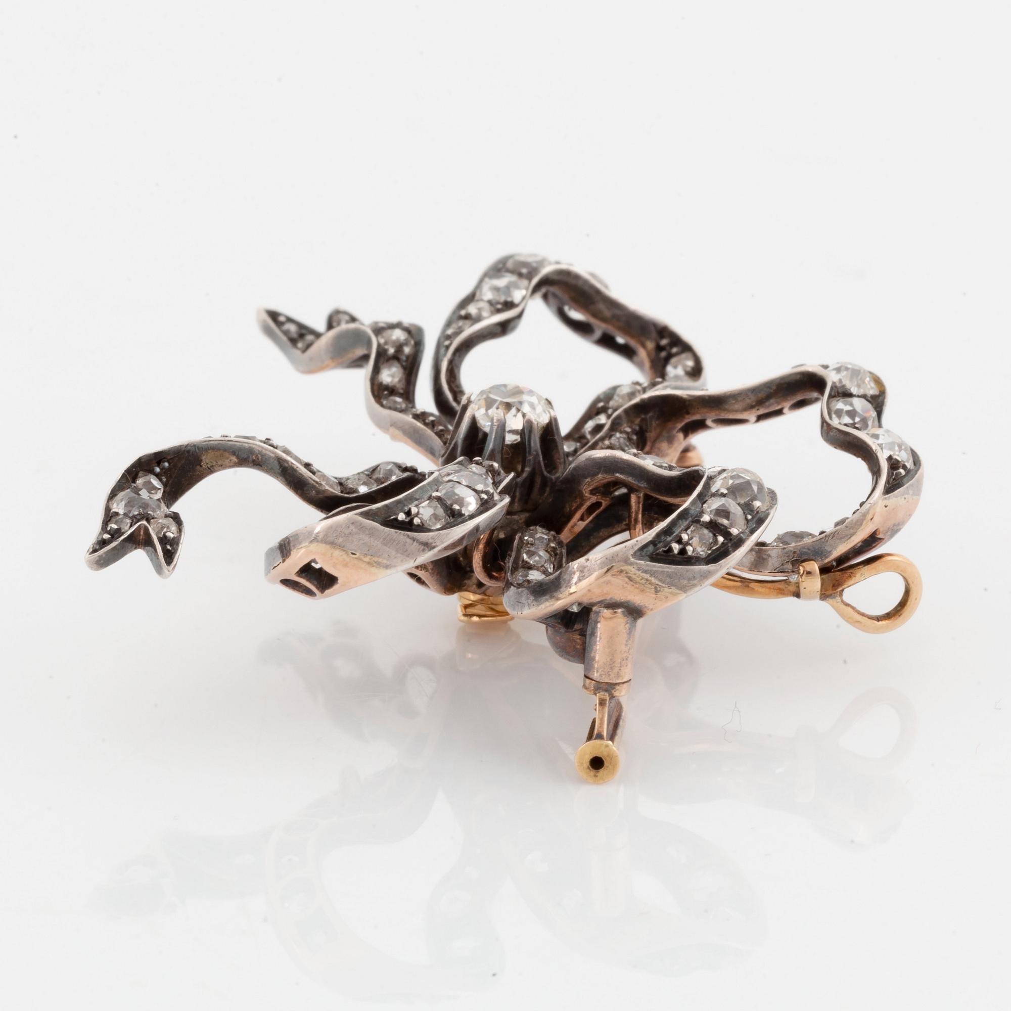 A silver and 14K gold bow brooch/pendant set with old- and rose-cut diamonds.
