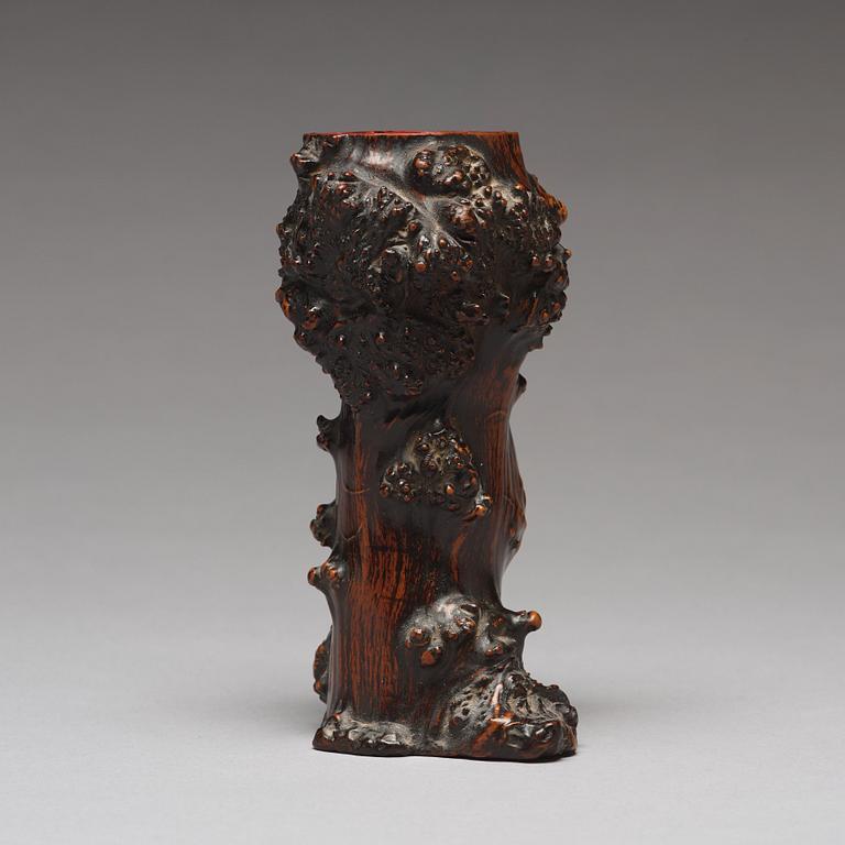 A Chinese wooden brush pot in the shape of a tree trunk.