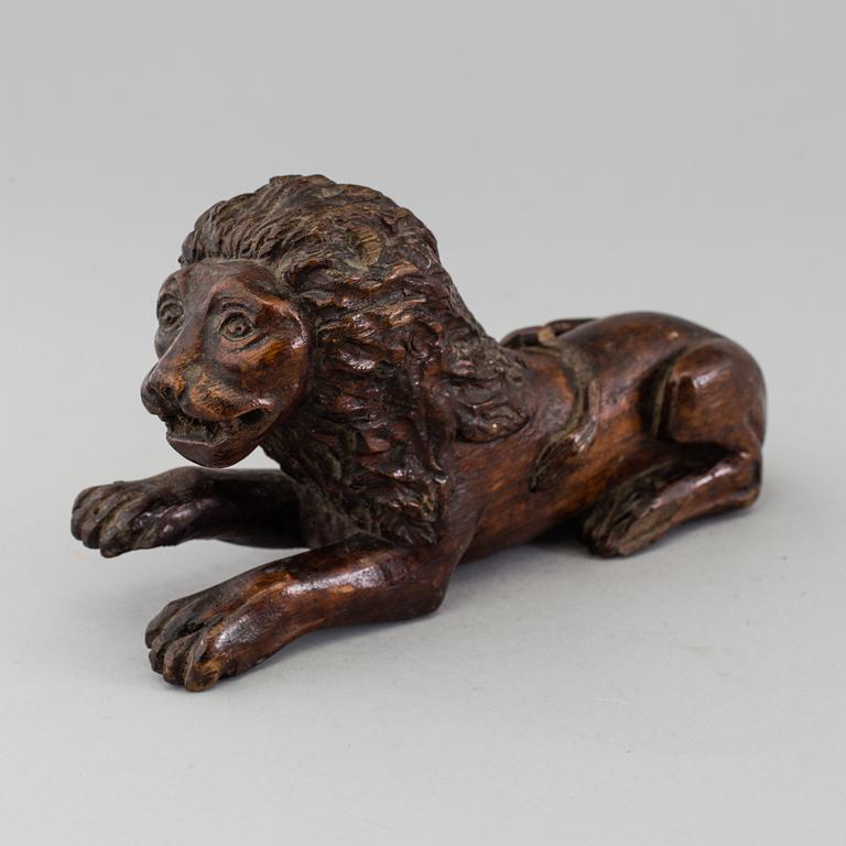 A 17TH CENTURY CARVED WOOD FIGURE OF A LION.