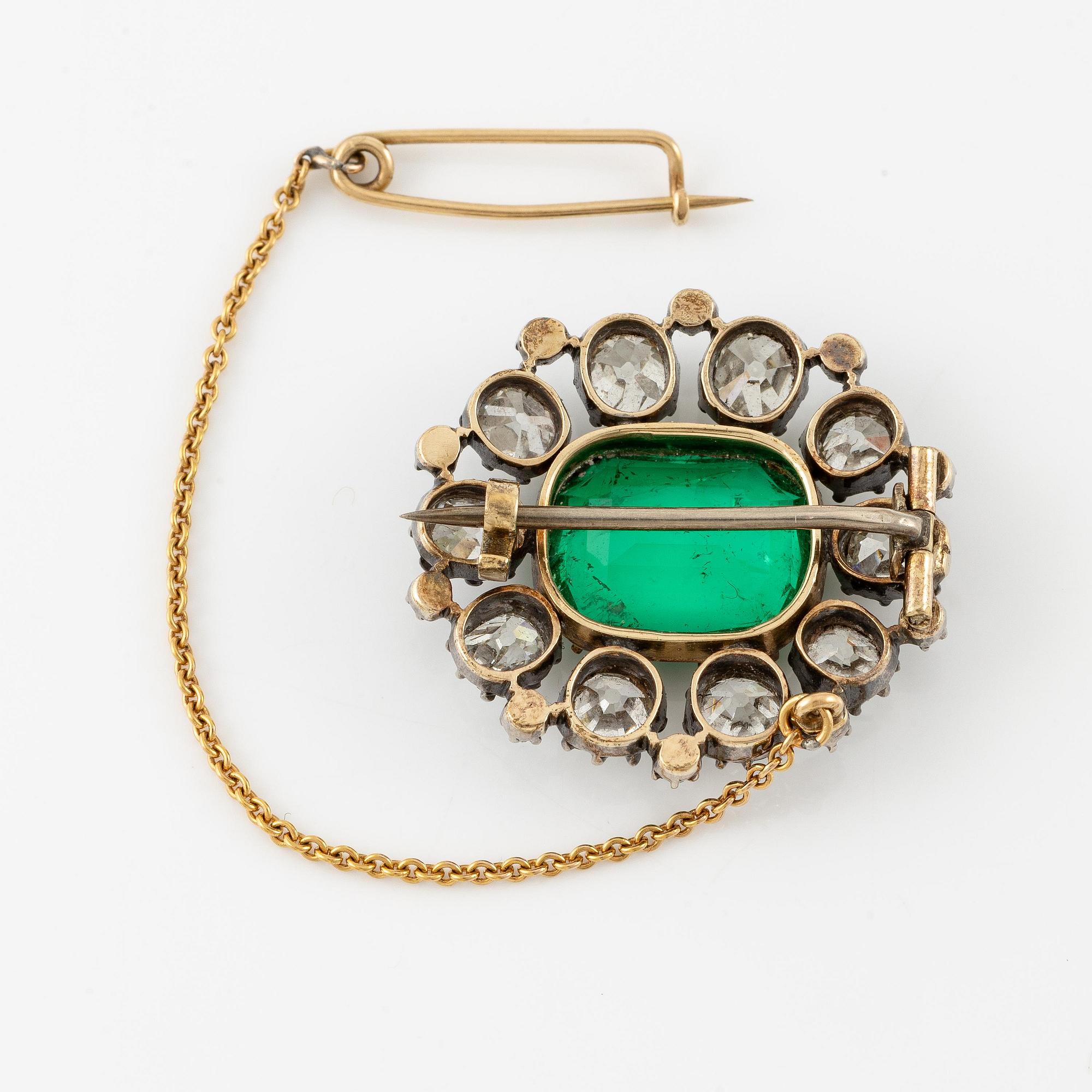 A brooch in silver and 14K gold with a step-cut emerald.
