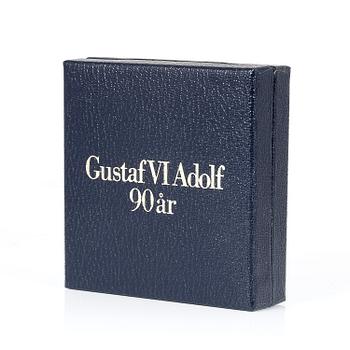 MINNESMEDALJ, 18 k guld, "Gustaf VI Adolf 90 år", formgiven av Rune Karlzon, enligt cert. nr. 000158. Vikt ca 65 g.