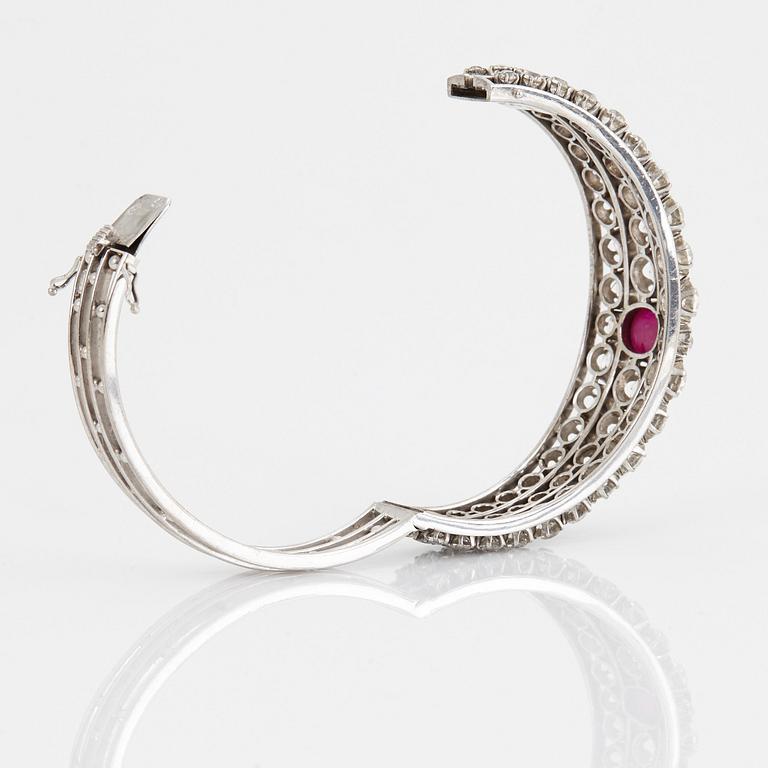 An 18K white gold bangle set with a cabochon-cut ruby and old-cut diamonds.