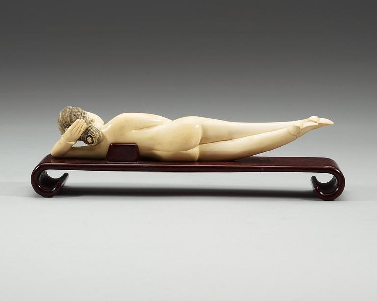 A ivory figure of a reclining 'Doctors Lady' on a wooden stand, Qing dynasty, circa 1900.