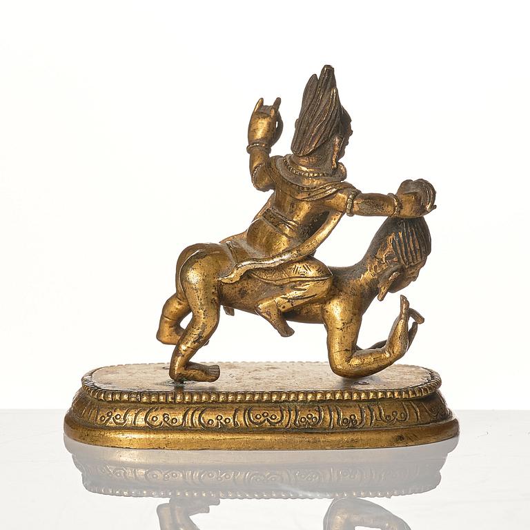 A small gilt bronze figure wrathful deity riding on a corpse, Tibeto-Chinese, 18th Century.