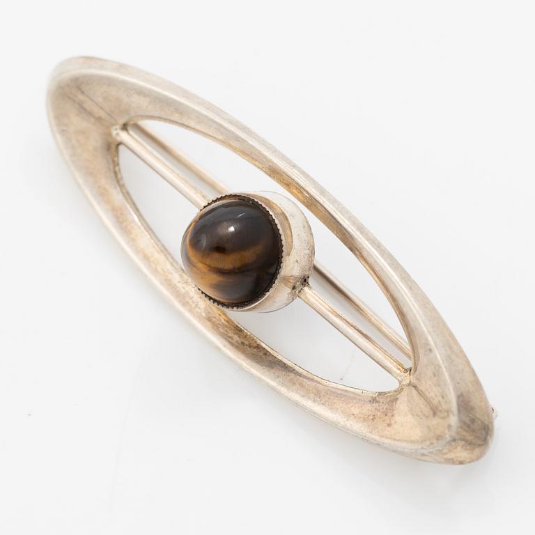 Four silver jewellery pieces: three brooches and a pair of cufflinks. With rose quartz and tiger’s eye. Finnish designers.