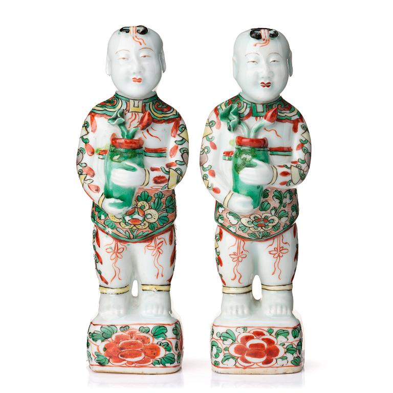 A pair of wucai decorated porcelain figurines of boys with flowers, Qing dynasty, Kangxi (1662-1722).