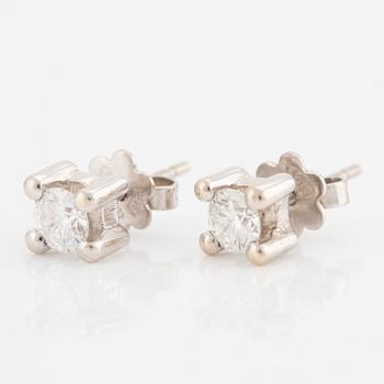 A pair of earrings in 18K white gold set with two round brilliant-cut diamonds.