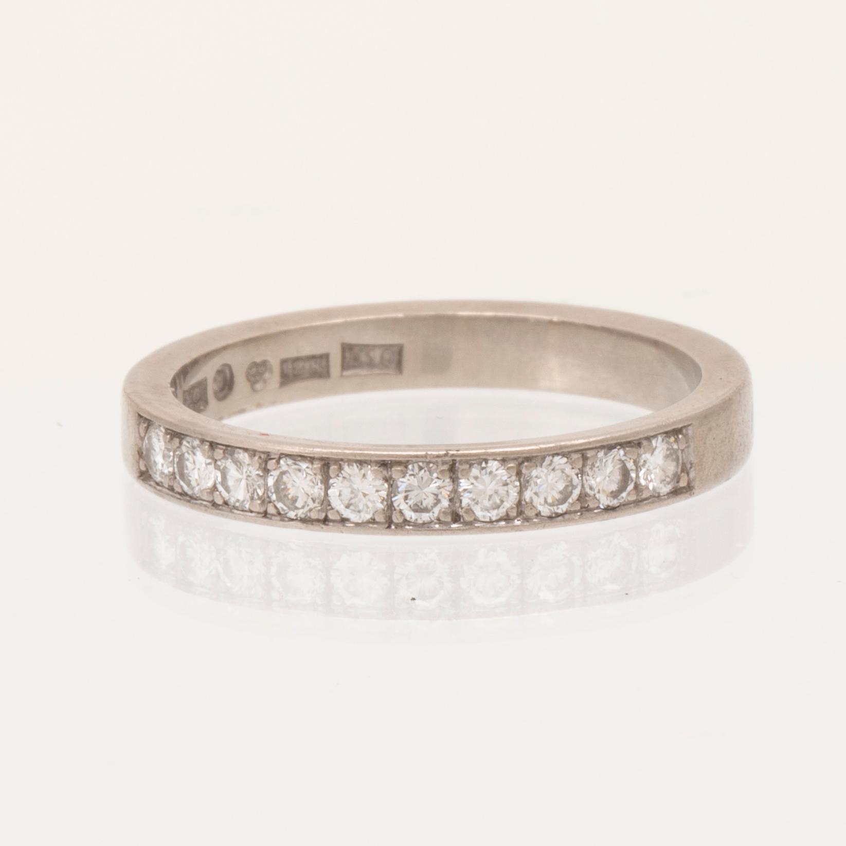 An 18K white gold half eternity ring set with round brilliant-cut diamonds.