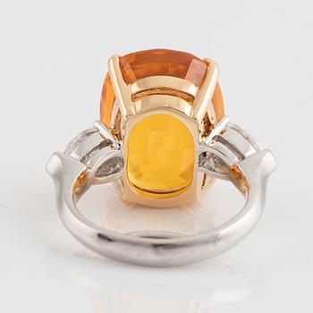 An 18K white gold ring set with a cushion shaped orange-yellow sapphire.