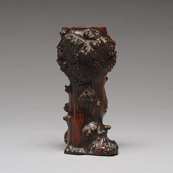 A Chinese wooden brush pot in the shape of a tree trunk.