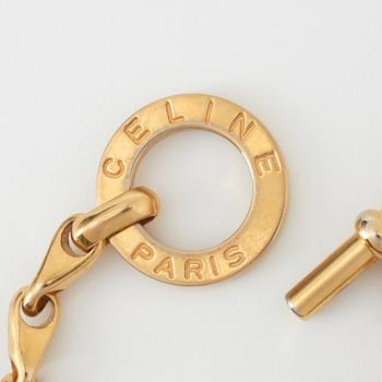 CÈLINE, a gold coloured bracelet.