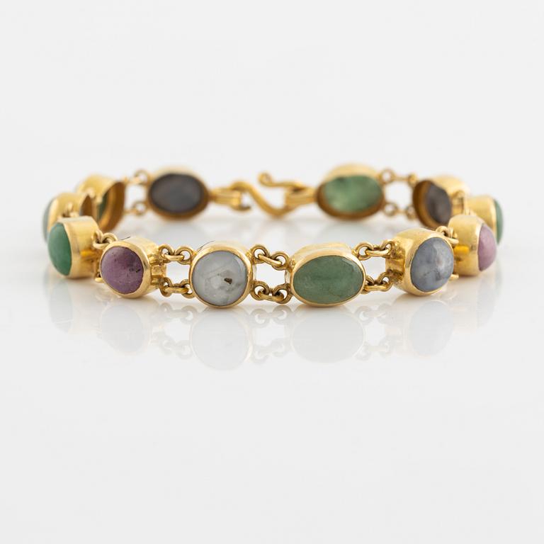 An 18K gold bracelet set with cabochon-cut emeralds and corundum.