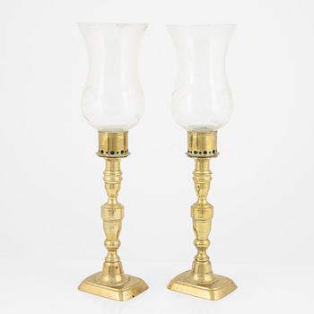 A pair of brass candlesticks with storm glass, 19th century.