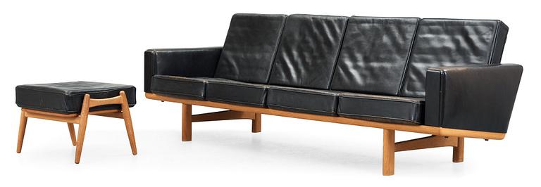 A Hans J Wegner oak and black leather four-seated sofa and stool, Getama, Denmark 1960's.