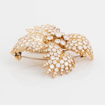 A Van Cleef & Arpels flower brooch in 18K gold set with round brilliant-cut diamonds.
