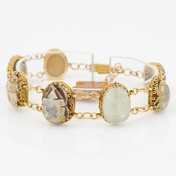 Bracelet in 14K gold with various minerals and scarab-shaped charms.