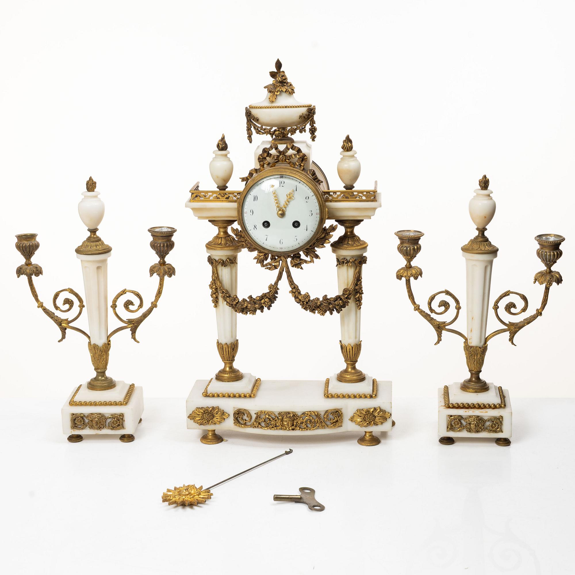 A Louis XVI-style mantle clock and a pair of candelabras. Early 20th century.