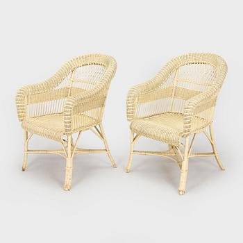 A mid-20th-century three-piece rattan furniture set including two armchairs, and a table.