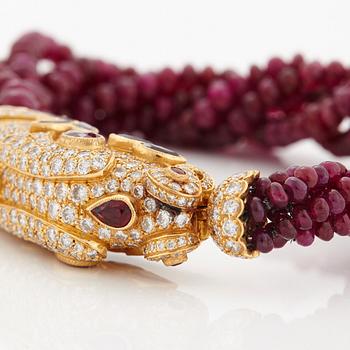 A Cartier chimera head bracelet in 18K gold set with round brilliant-cut diamonds and faceted rubies.