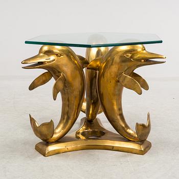 A brass and glass coffee table decorated with dolphins.