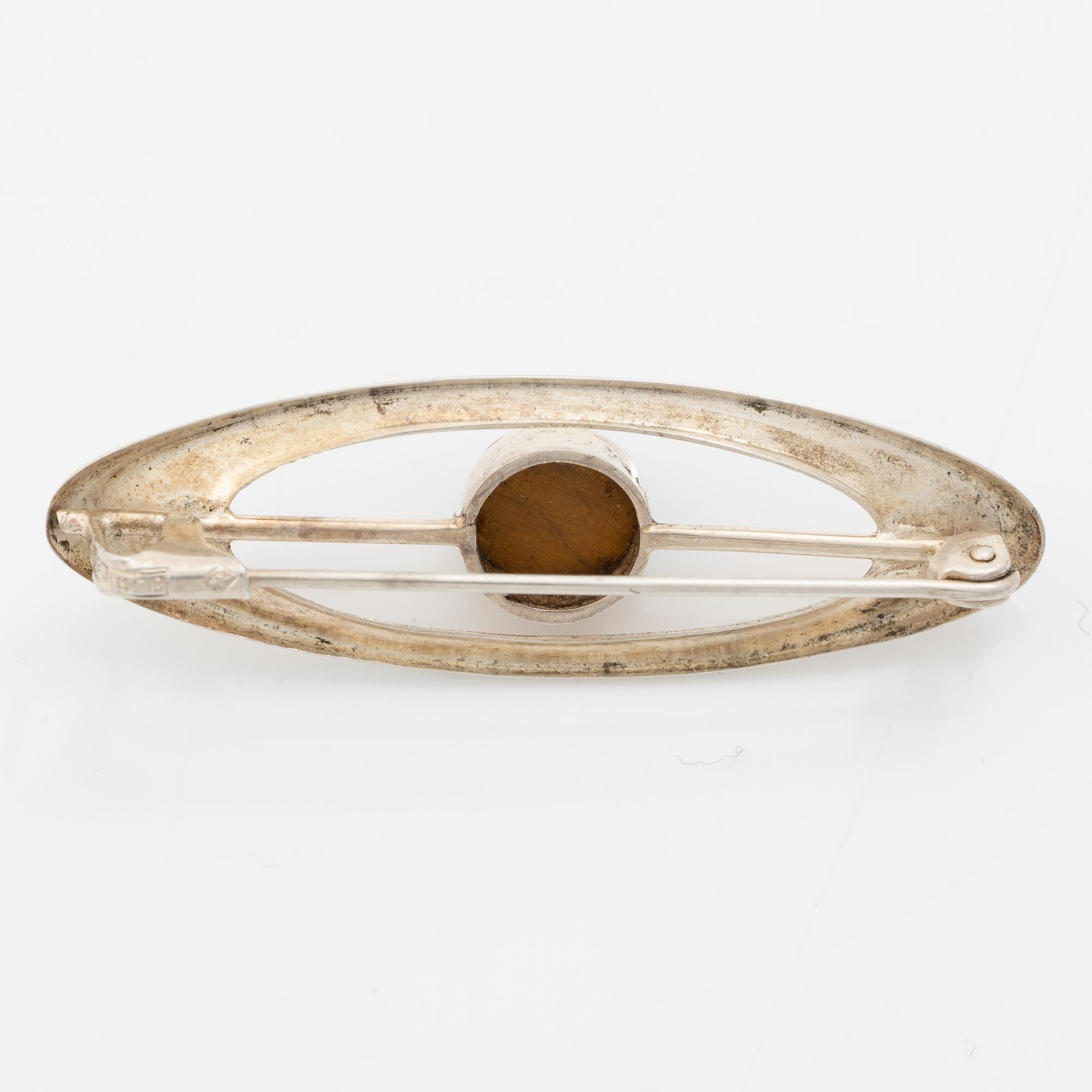 Four silver jewellery pieces: three brooches and a pair of cufflinks. With rose quartz and tiger’s eye. Finnish designers.
