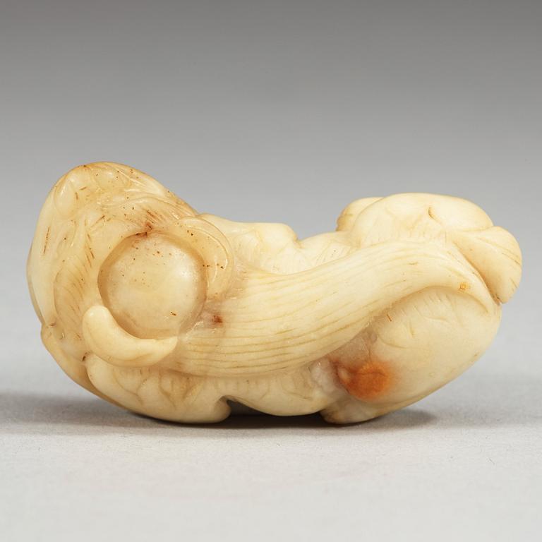 A Chinese nephrite figure of a reclining buddhist lion with a coin.