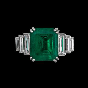 1168. A step cut emerald app 6 cts, flanked by diamonds.