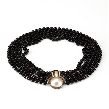 604. CARTIER, an onyx pearl necklace with silver and gold lock with a marbé pearl.