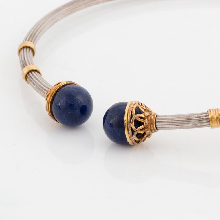 An Ilias Lalaounis demi parure comprising a necklace, a bracelet and a ring in silver and 18K gold set with sodalite.