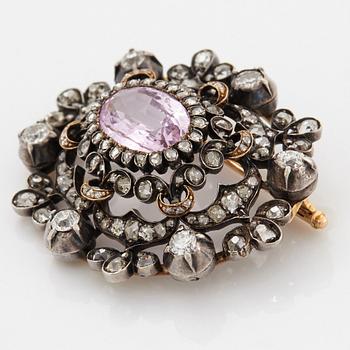A 14K gold and silver brooch set with an oval faceted pink topaz and old- and rose-cut diamonds.