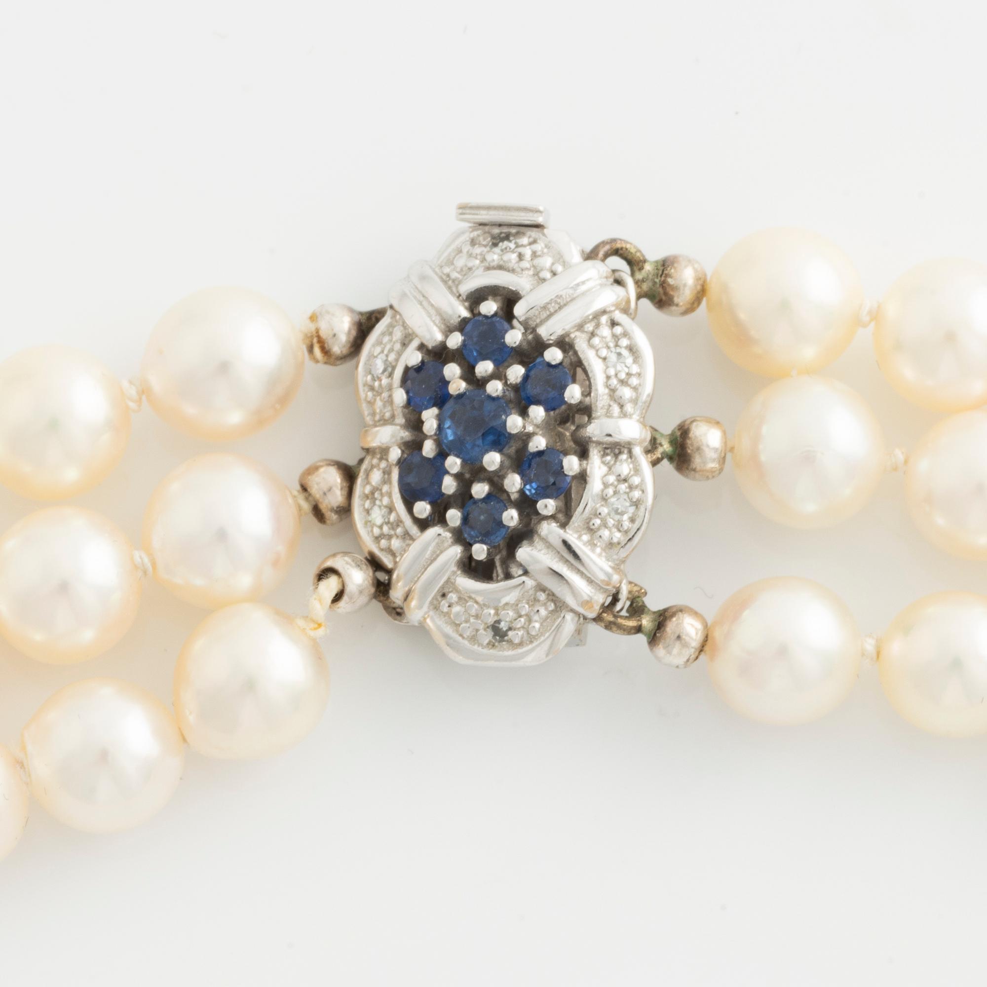 Necklace, three-stranded with cultured pearls, clasp in white gold with sapphires and small diamonds.