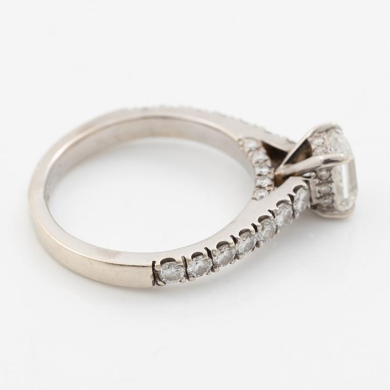 18K white gold ring set with an emerald-cut diamond and round brilliant-cut diamonds.