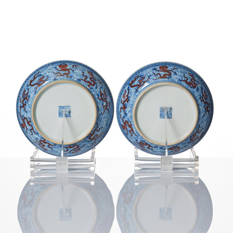 A pair of blue and white and iron red decorated dragon dishes, Qing dynasty with Qianlong mark.