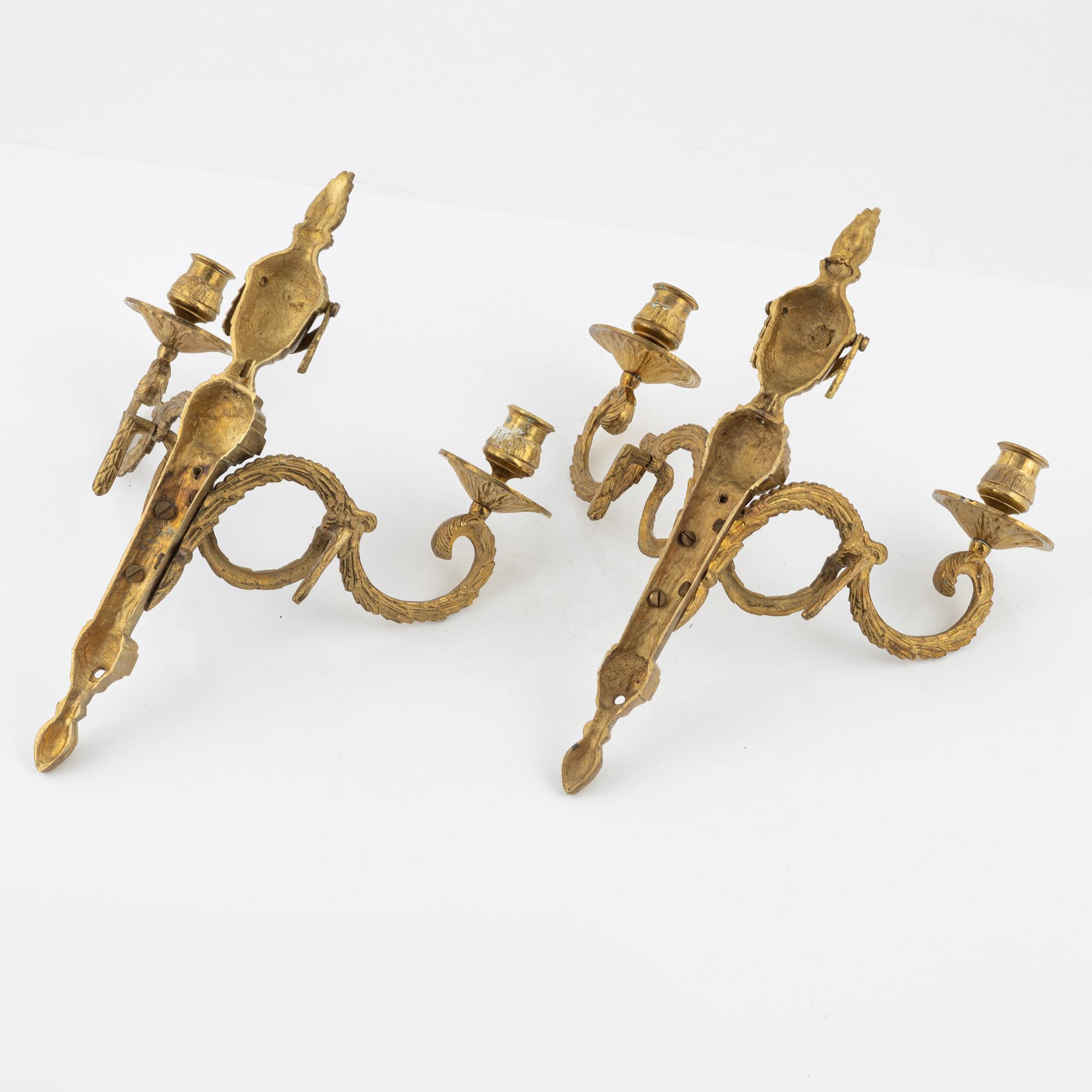 A pair of brass Louis XVI-style two-light wall lights, early 20th Century.