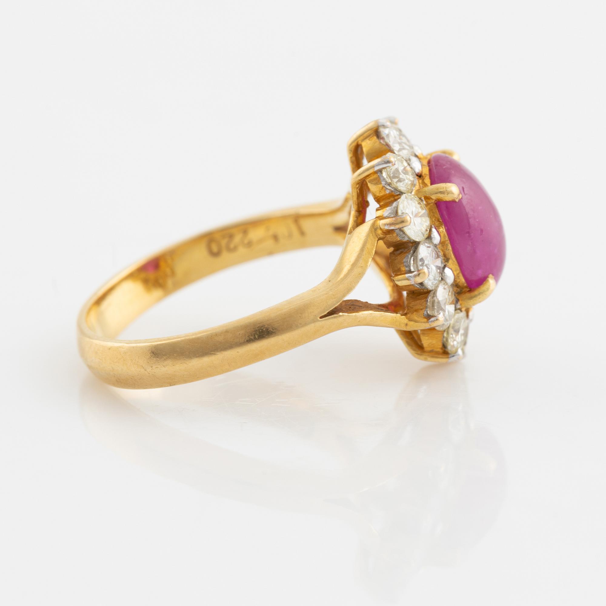 An 18K gold ring set with a cabochon-cut ruby and round brilliant-cut diamonds.