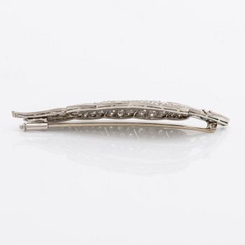 A platinum brooch set with round brilliant-cut diamonds and emeralds.