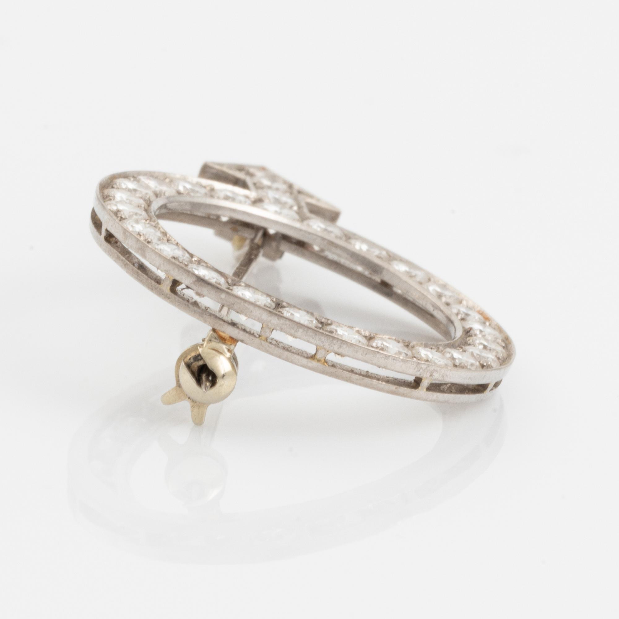 An 18K white gold brooch set with round brilliant-cut diamonds.