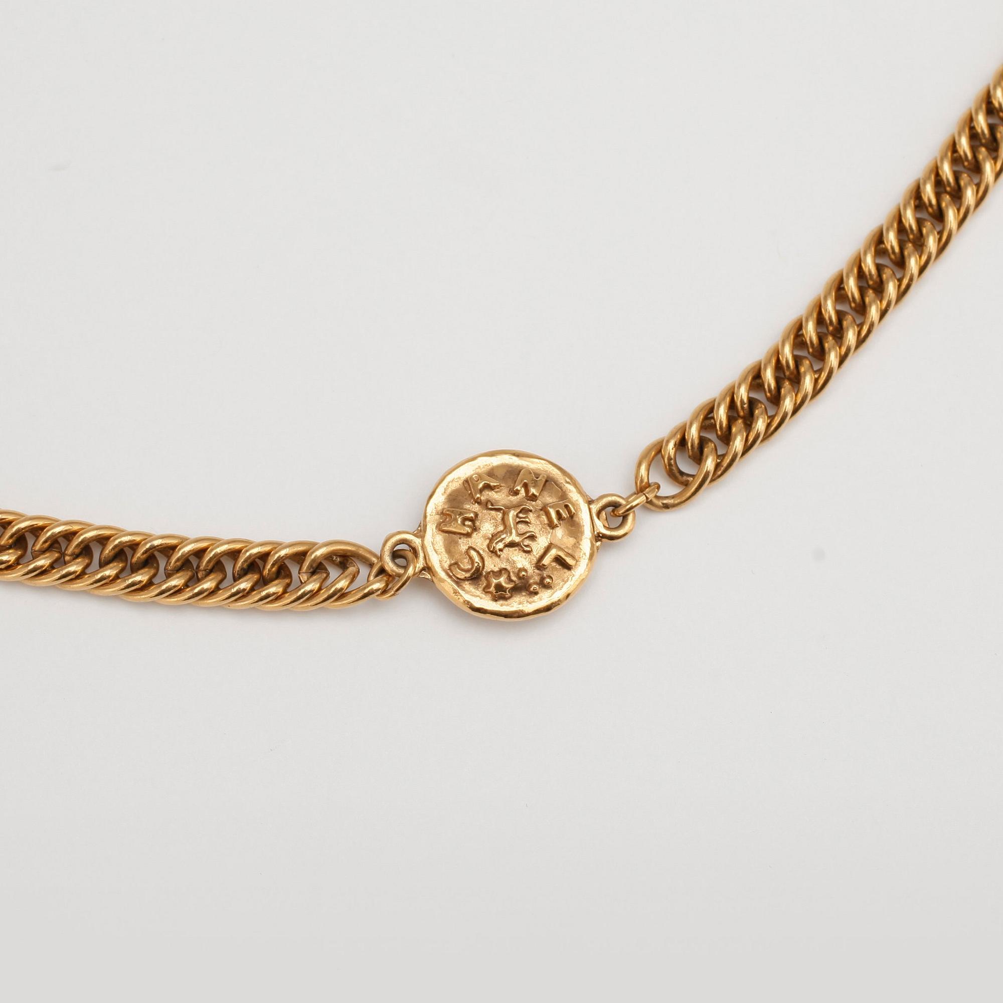 CHANEL, a gold colored medallion necklace.