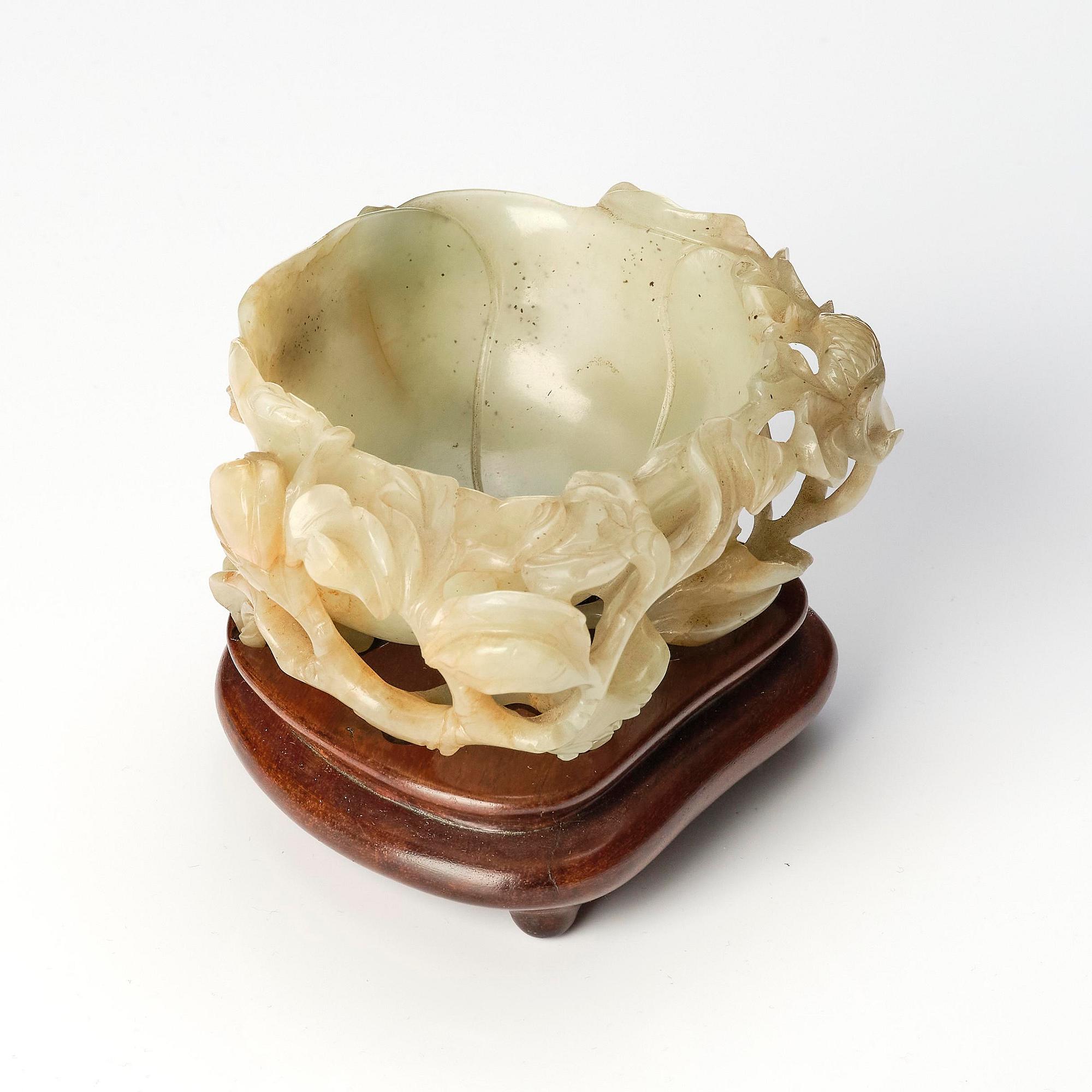A carved Chinese nephrite cup in the shape of a lotus leaf, late Ming dynasty.
