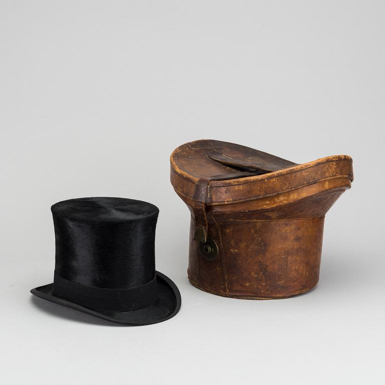 A LEATHER HAT BOX WITH A TOP HAT, 19th century latter part / turn of the century 1900.