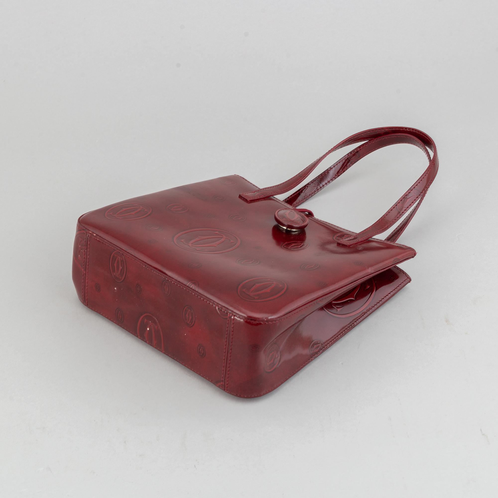 Cartier, a burgundy patent leather handbag and wallet.