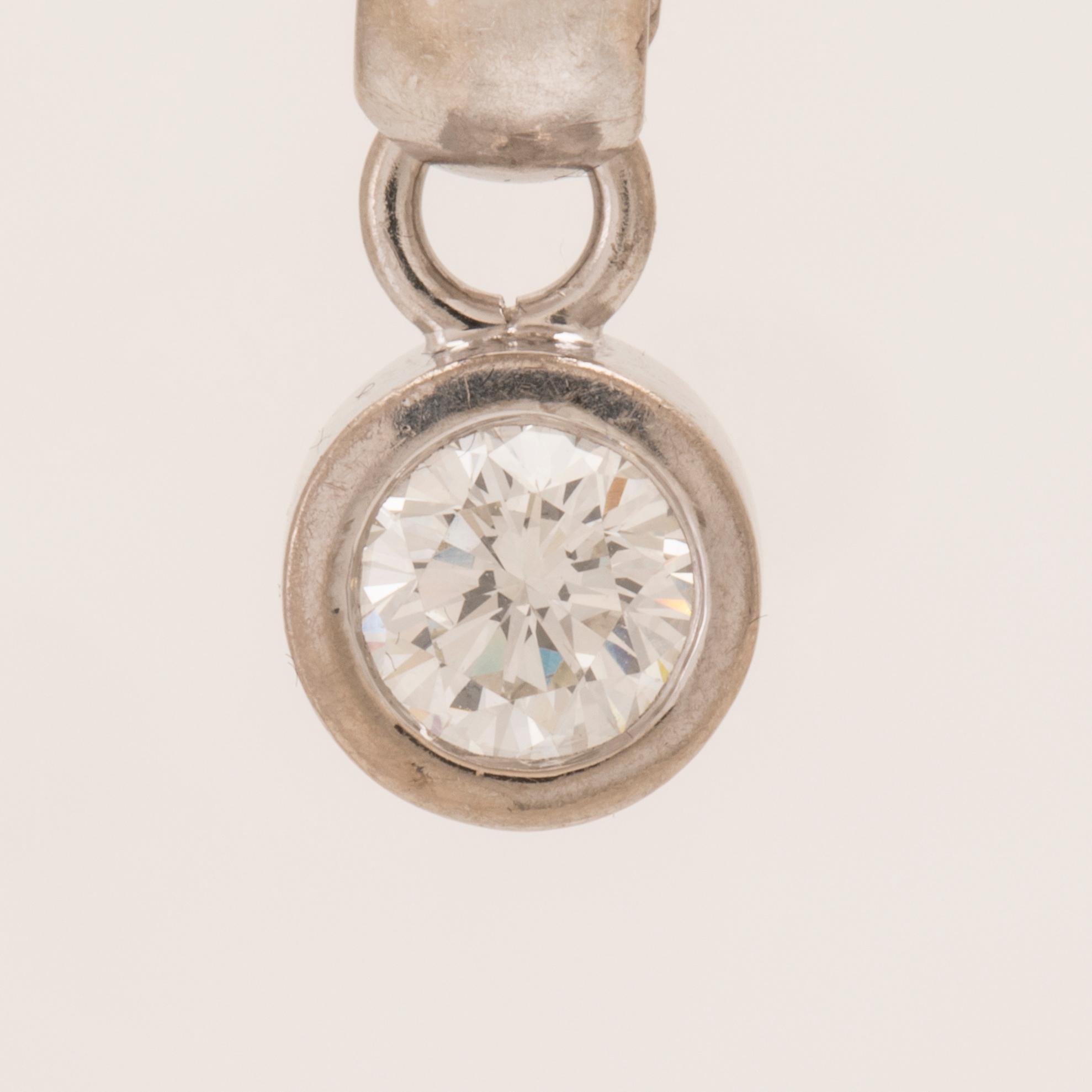 An 18K white gold pendant set with a round brilliant-cut diamond.