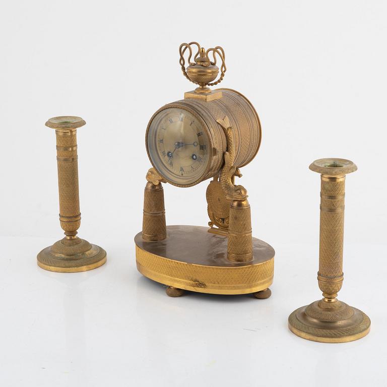 An Empire-style gilt bronze mantel clock and a pair of candlesticks, 20th century.